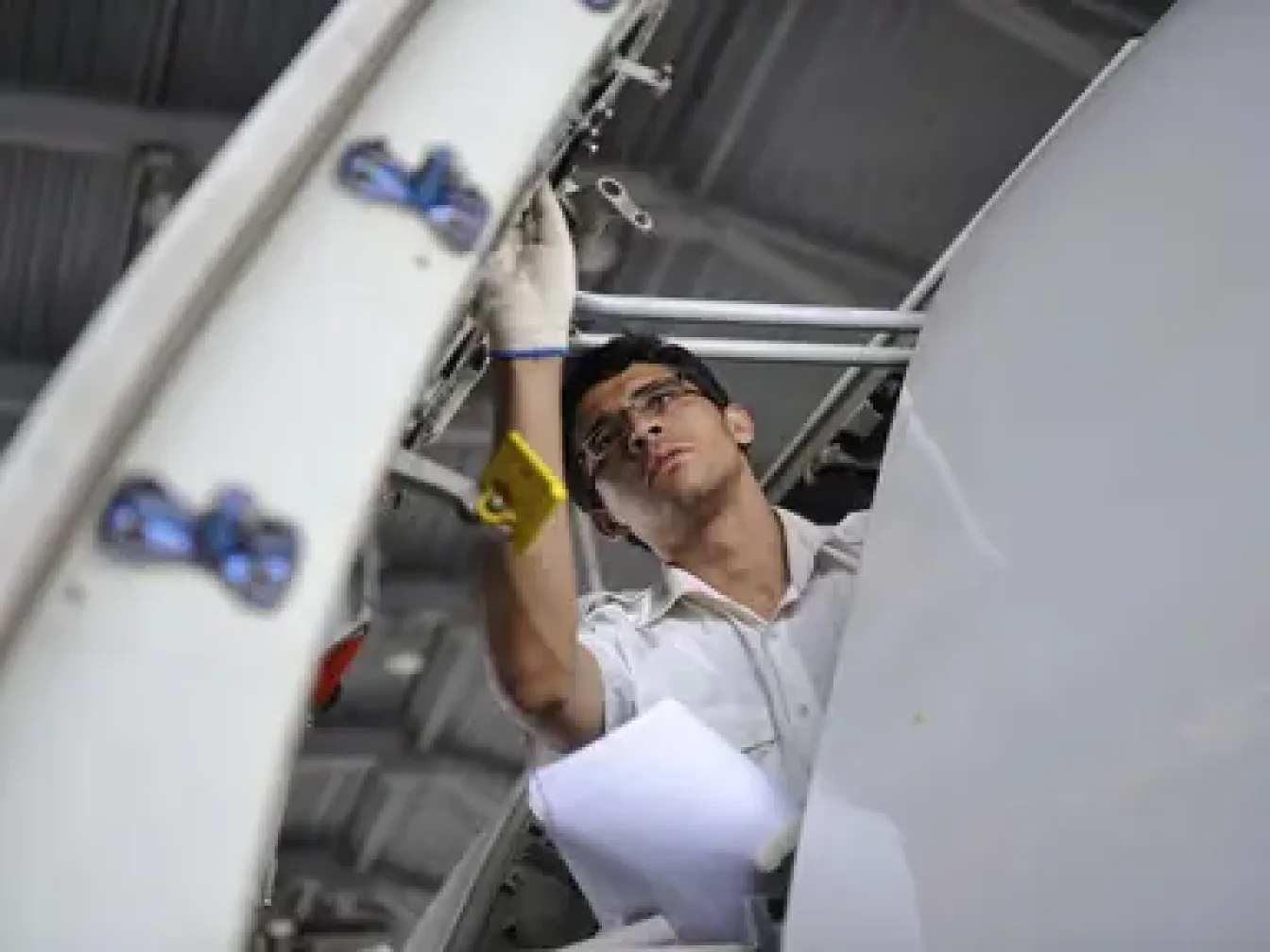 A man with work glaces trying to fix a part in a plan